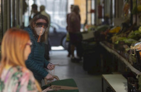 ep una mujer protegida con mascarilla y pantalla protectora guarda turno en una fruteria durante el