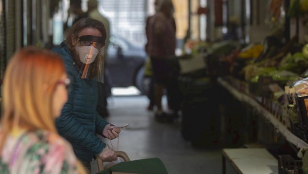 ep una mujer protegida con mascarilla y pantalla protectora guarda turno en una fruteria durante el