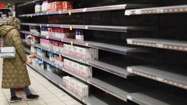 ep una mujer frente a la estanteria de leche que le faltan algunos productos