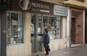 ep una mujer en la puerta de una tienda de articulos de peluqueria segun el plan de desescalada del