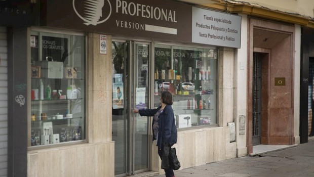 ep una mujer en la puerta de una tienda de articulos de peluqueria segun el plan de desescalada del