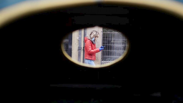 ep una mujer camina por la calle protegida con mascarilla y guantes sujetando su movil durante la