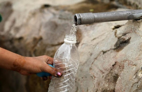 ep mujer llenando una botella de agua en un grifo en la calle