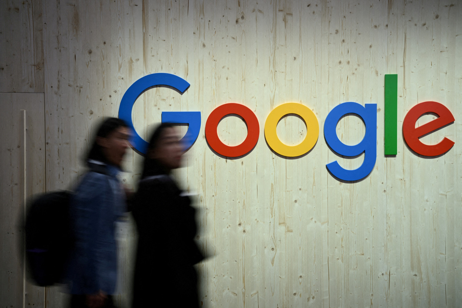 des personnes marchent a cote d un logo google 