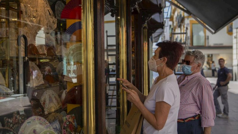 Dos personas con mascarilla observan el escaparate de una tienda durante el tercer día de la fase 2 . En Sevilla, (Andalucía, España), a 27 de mayo de 2020. | María José López - Europa Press ep dos personas con mascarilla observan el escaparate de una tienda durante el tercer dia de la fase