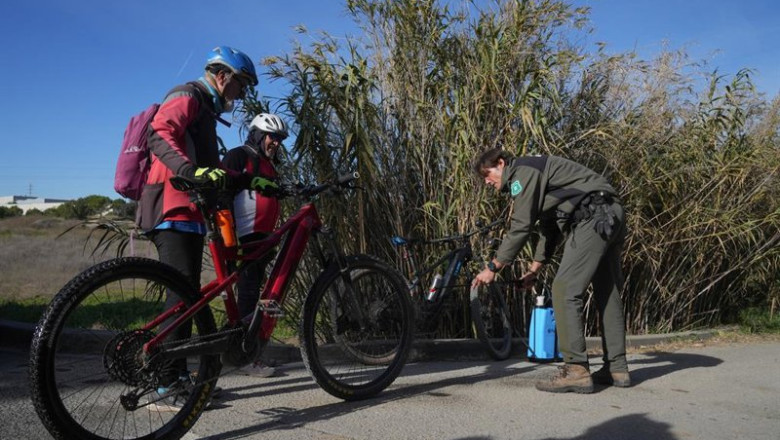 ep un agente rural de los mossos desquadra desinfecta las bicicletas de unos ciclistas en las zonas