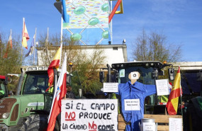ep un tractor sostiene un pale con una pancarta en la que se lee si el campo no produce la ciudad no
