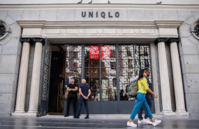ep dos personas pasan por delante de la entrada de una tienda uniqlo en la gran via la segunda que