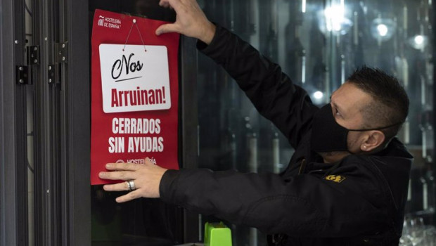 ep un trabajador de hosteleria coloca un cartel donde se lee nos arruinan cerrados sin ayudas