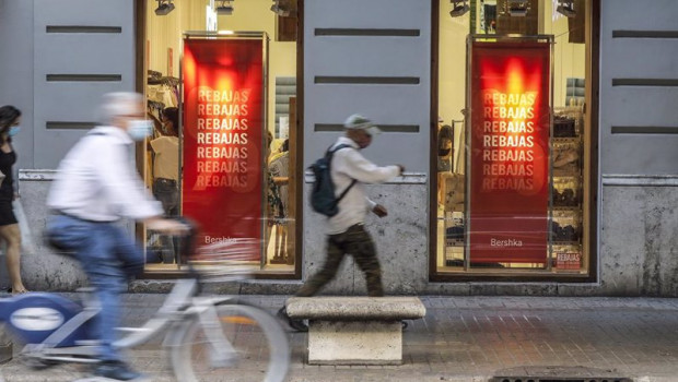 ep varias personas pasan al lado del escaparate de una tienda donde se observan carteles indicativos