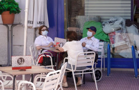 ep ancianos con mascarilla conversan sentados en la terraza de un bar
