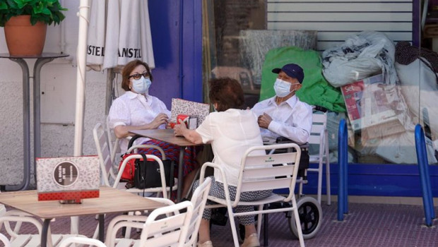 ep ancianos con mascarilla conversan sentados en la terraza de un bar