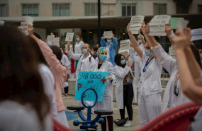 ep decenas de miembros del personal sanitario protegidos con mascarilla sostienen carteles durante