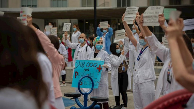 ep decenas de miembros del personal sanitario protegidos con mascarilla sostienen carteles durante