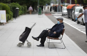 ep un hombre de edad avanzada espera en un banco protegido con mascarilla y con un carro de la