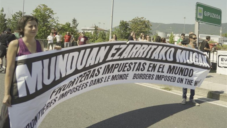 Una mujer sostiene una pancarta en la manifestación en la que han participado cientos de personas contra el G7 que ha partido de la rotonda Flore de Hendaya y concluirá en Irún. | H.Bilbao - Europa Press ep una mujer sostiene una pancarta en la manifestacion en la que han participado cientos de personas