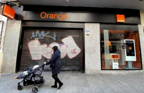 ep una mujer pasea frente a una tienda de de la compania telefonica orange
