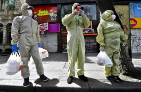 ep tres personas ataviadas con trajes protectores en las calles de la paz tras volver de las compras