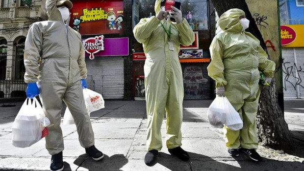 ep tres personas ataviadas con trajes protectores en las calles de la paz tras volver de las compras