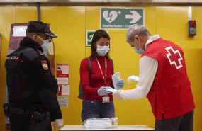 ep un agente de la policia nacional vigila el reparto de mascarillas de un voluntario de la cruz
