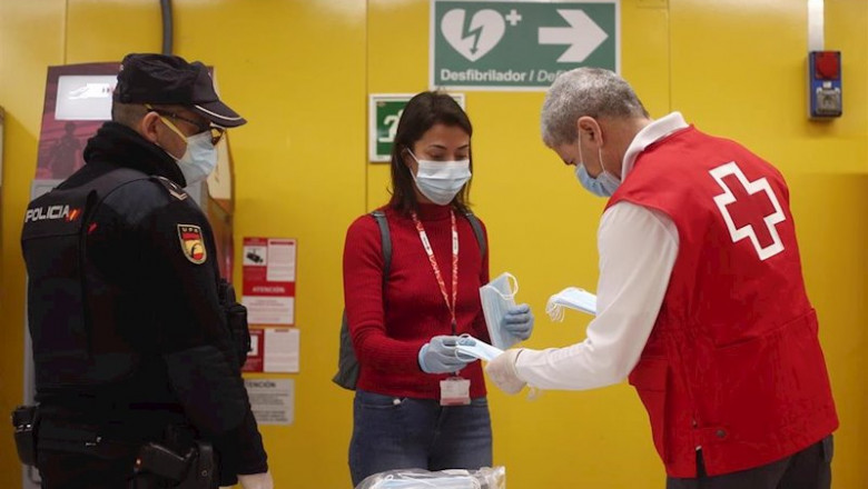 ep un agente de la policia nacional vigila el reparto de mascarillas de un voluntario de la cruz