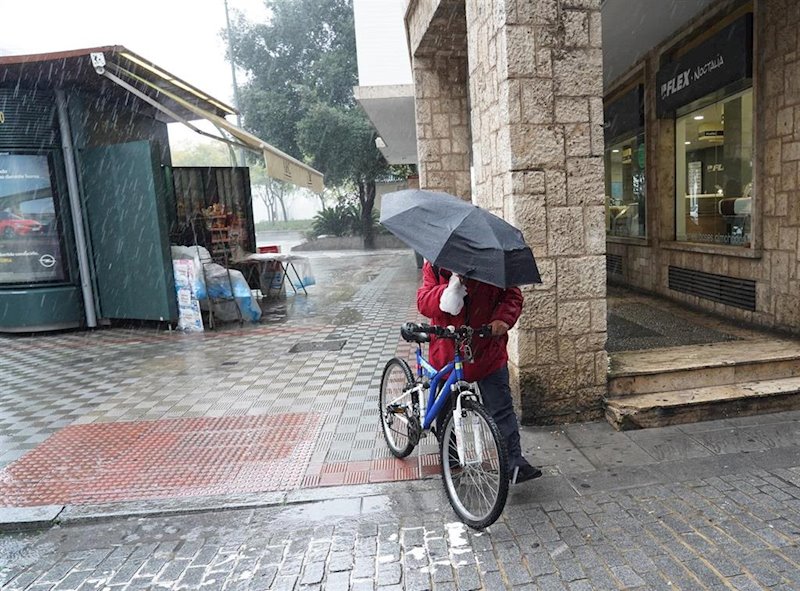 ep un ciclista con un pagaguas resguardandose de la lluvia y el viento