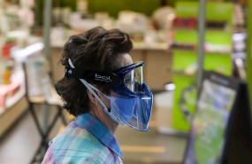 ep una mujer protegida con mascarilla y gafas protectoras pasa junto a una tienda abierta en