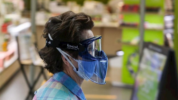 ep una mujer protegida con mascarilla y gafas protectoras pasa junto a una tienda abierta en