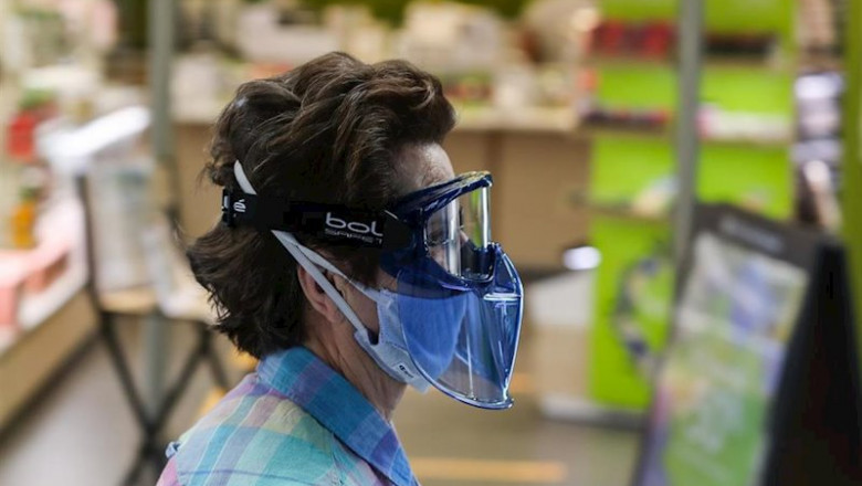 ep una mujer protegida con mascarilla y gafas protectoras pasa junto a una tienda abierta en ep una mujer protegida con mascarilla y gafas protectoras pasa junto a una tienda abierta en