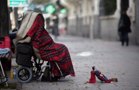 ep una persona en silla de ruedas y tapada con una manta pide dinero en una calle de madrid