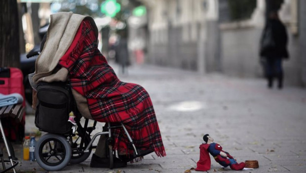 ep una persona en silla de ruedas y tapada con una manta pide dinero en una calle de madrid