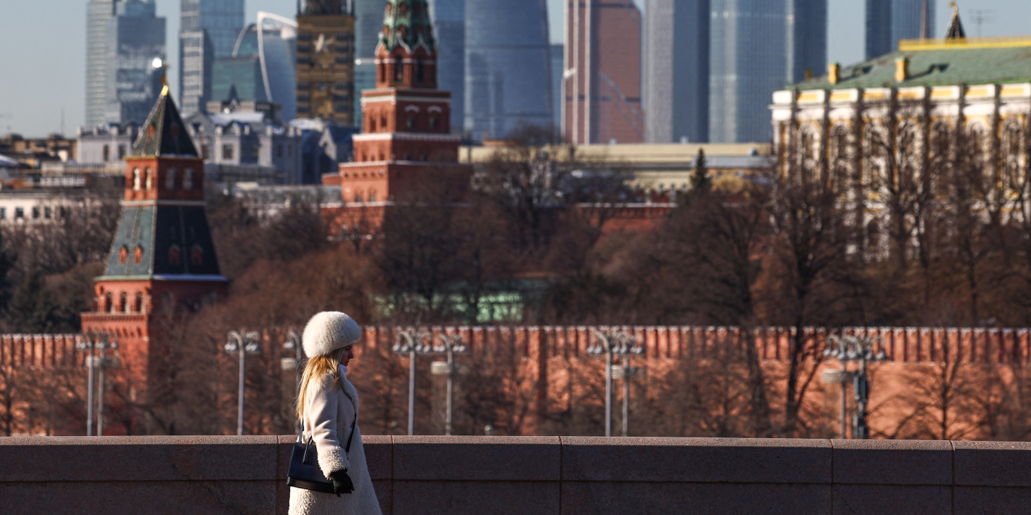 une femme marche le long d un pont avec le centre d affaires moscow city et le mur du kremlin visibles en arriere plan par une journee ensoleillee a moscou 