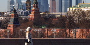une femme marche le long d un pont avec le centre d affaires moscow city et le mur du kremlin visibles en arriere plan par une journee ensoleillee a moscou 